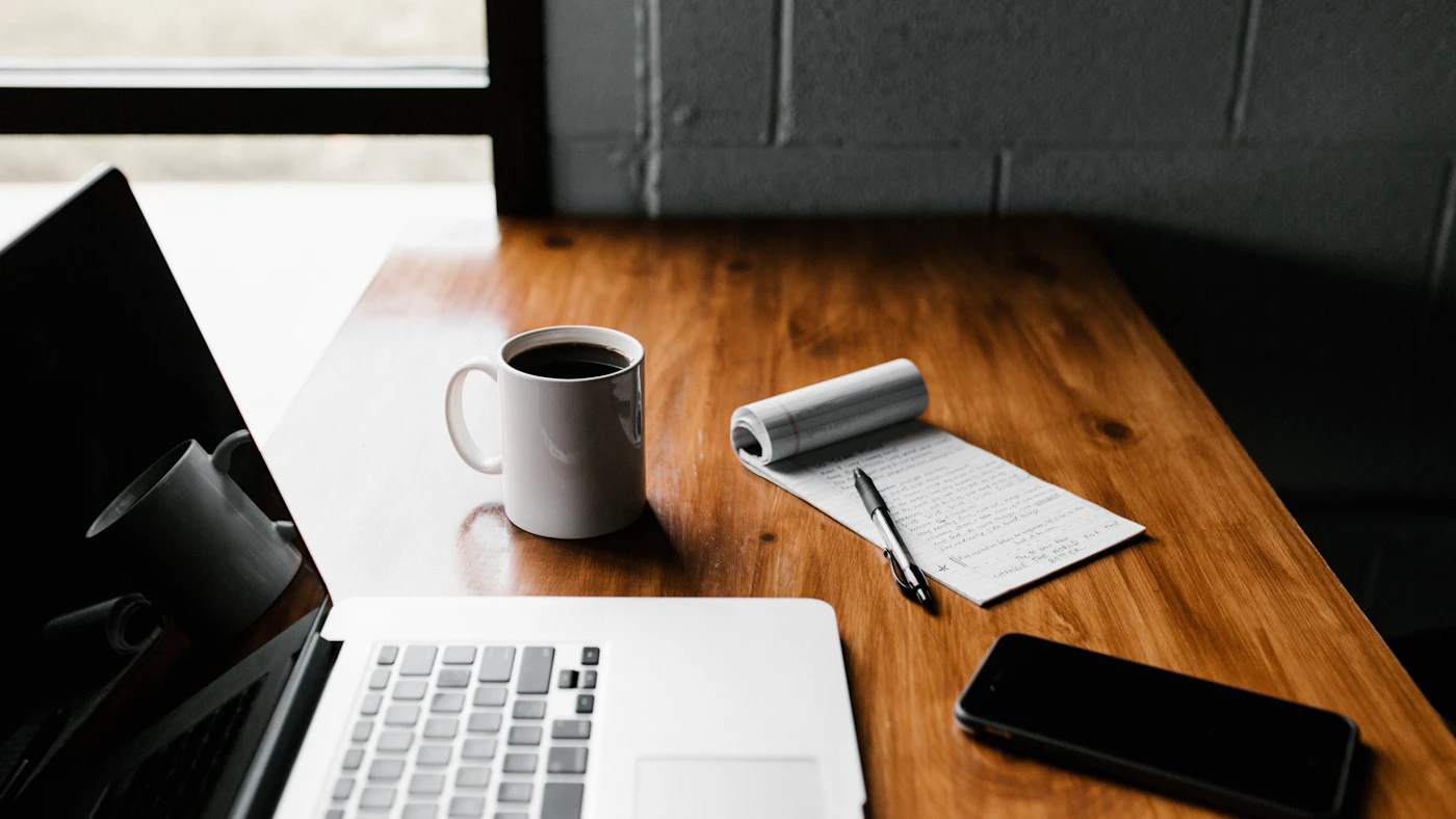 Laptop and open notebook on a desk for planning digital marketing.