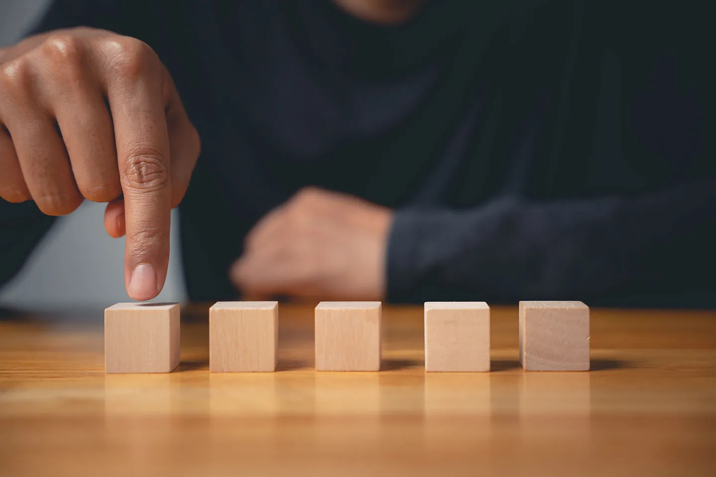 A hand selecting one wooden block from a row of options.